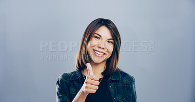 Buy stock photo Portrait, thumbs up and woman in studio, smile and agreement on gray background. Face, happy person and model with hand gesture, like and icon with emoji, feedback and sign with promote and support