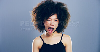 Buy stock photo Studio, woman and portrait with wink for goofy, emoji expression and carefree model with flirting. African female person, mouth and silly with funny personality, crazy and mockup by gray background