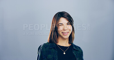 Buy stock photo Studio, woman and portrait with wink for silly, emoji expression and carefree model with flirting. Female person, smile and goofy with funny personality, secret and mockup space by gray background