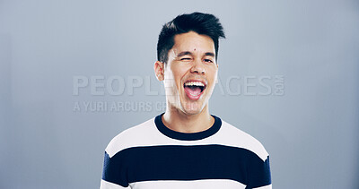 Buy stock photo Studio, man and portrait with wink for playful, emoji expression or carefree model with flirting. Male person, mouth or goofy with silly personality for mood, crazy or mockup space by gray background