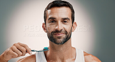Buy stock photo Smile, portrait and man brushing teeth on studio background for fresh breath, grooming or oral hygiene. Mockup space, morning routine or cleaning mouth for cavity prevention, plaque removal or health