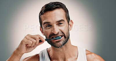 Buy stock photo Dental, portrait and man brushing teeth on studio background for oral hygiene and fresh breath. Mockup, morning routine and mouth care for cavity prevention, plaque removal and toothbrush with space