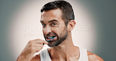 Buy stock photo Oral hygiene, portrait and man brushing teeth on studio background for fresh breath, grooming or self care. Mockup space, toothbrush or cleaning mouth for cavity prevention, routine or plaque removal