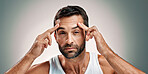 Man, face check and portrait in studio for skincare, wellness or cosmetics with space for antiaging. Male person, model and inspection for wrinkles, beauty treatment or routine on gray background