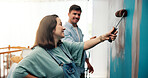 Couple, excited and painting a wall in home for diy renovation, living room makeover or house improvement. Interior design, people or support for decoration process, conversation or relationship