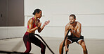 Fitness, personal trainer and man with battle ropes for workout, exercise or health. Muscle, woman and bodybuilder with coach for strength, power or clap for motivation with cardio challenge in city