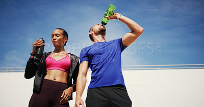 Buy stock photo Man, woman and fitness with drinking water in city, sky or hydration for training, health or recovery for wellness. People, couple and low angle with bottle, exercise or workout for break in summer