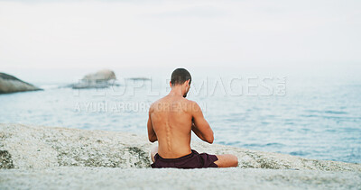 Buy stock photo Man, yoga and back by beach with meditation, peace and mindfulness on rock in morning for wellness. Person, breathing space and self care routine with zen, chakra and water by ocean in New Zealand