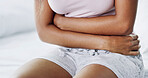 Woman, hands and sick on bed with stomach ache, menstruation cramps and IBS symptoms. Girl, discomfort and health risk in home bedroom with tummy pain, endometriosis and warm compress for relief
