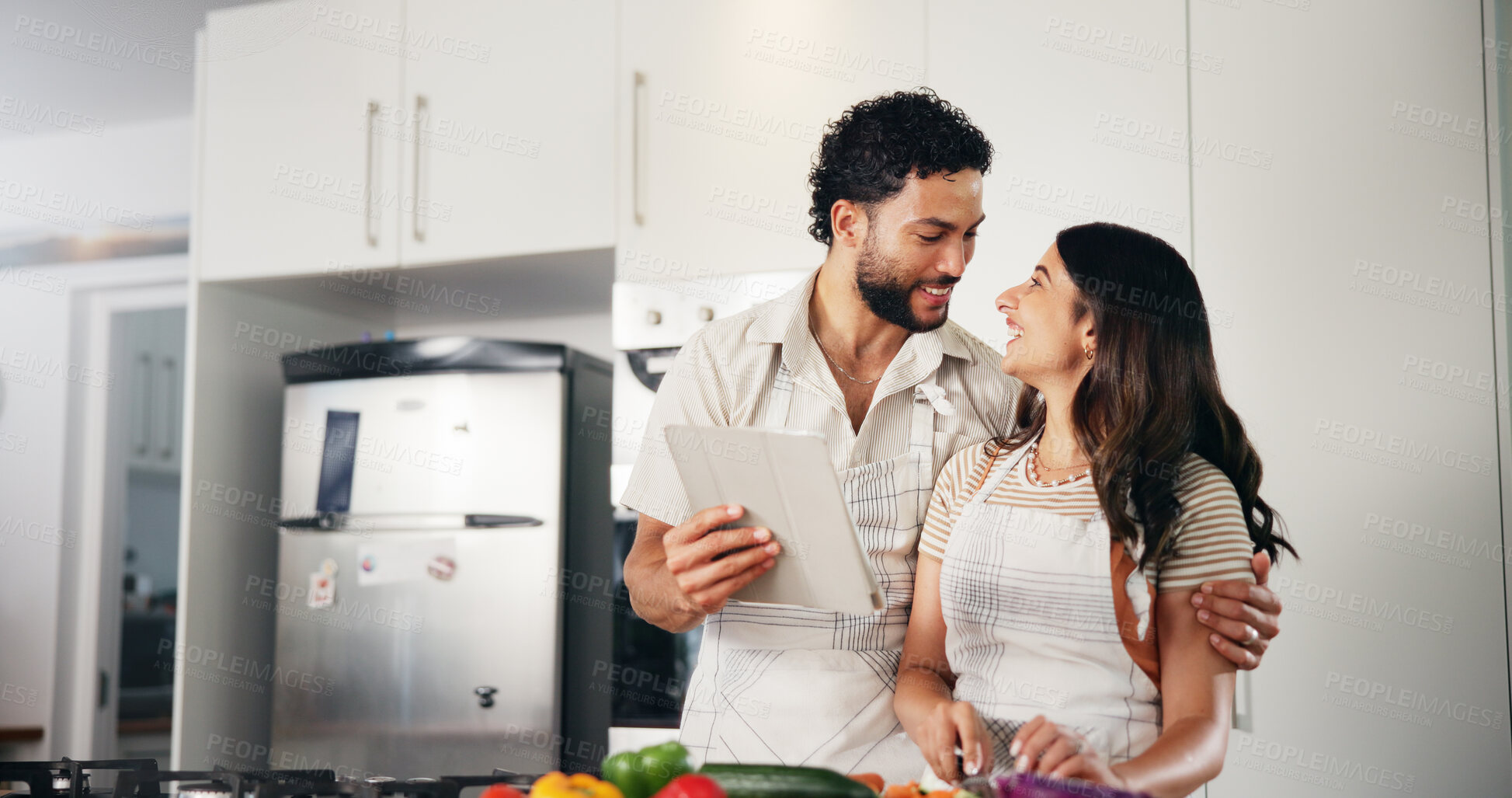 Buy stock photo Couple, tablet or hug in kitchen with food, meal prep or support for healthy diet. Happy man, woman or tech in home for recipe, conversation for dinner or research for nutritional value with love
