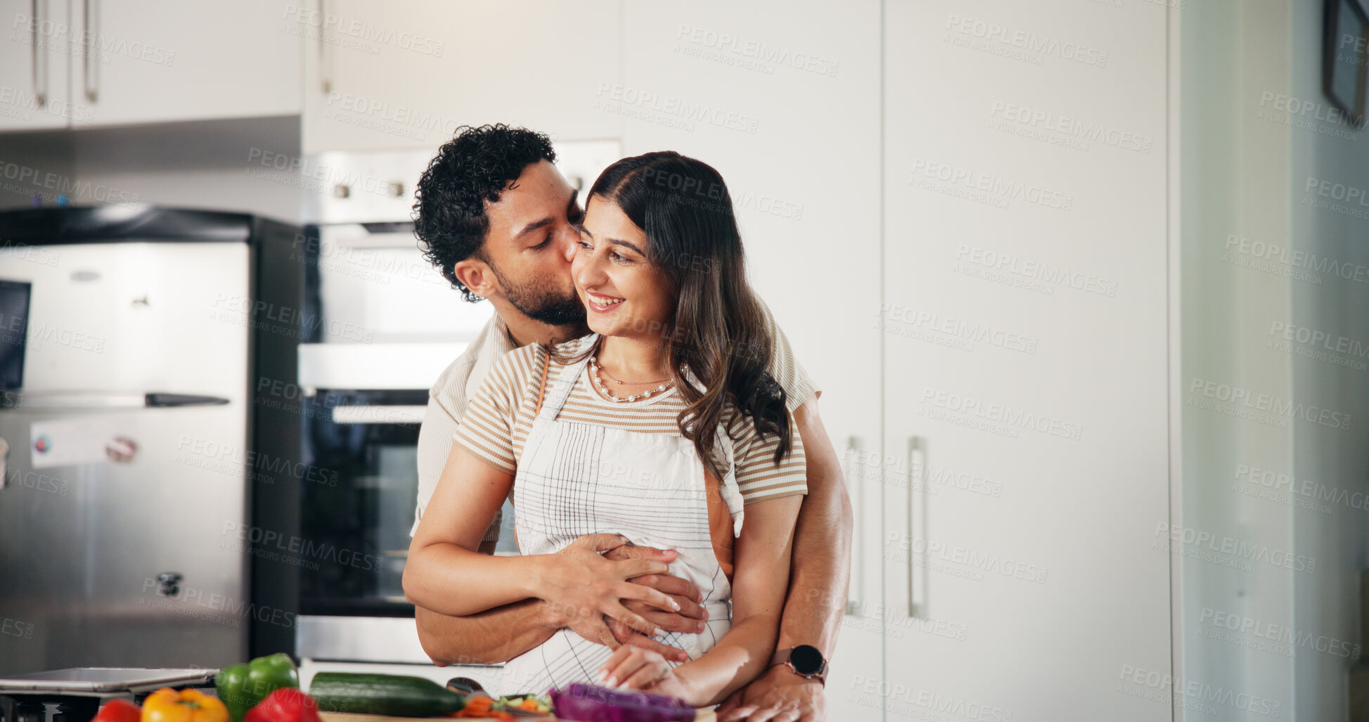 Buy stock photo Love, kiss and cooking with couple in kitchen for health, food and vegetables recipe. Hug, bonding and nutrition ingredients with man and woman helping at home for meal prep, wellness and lunch menu
