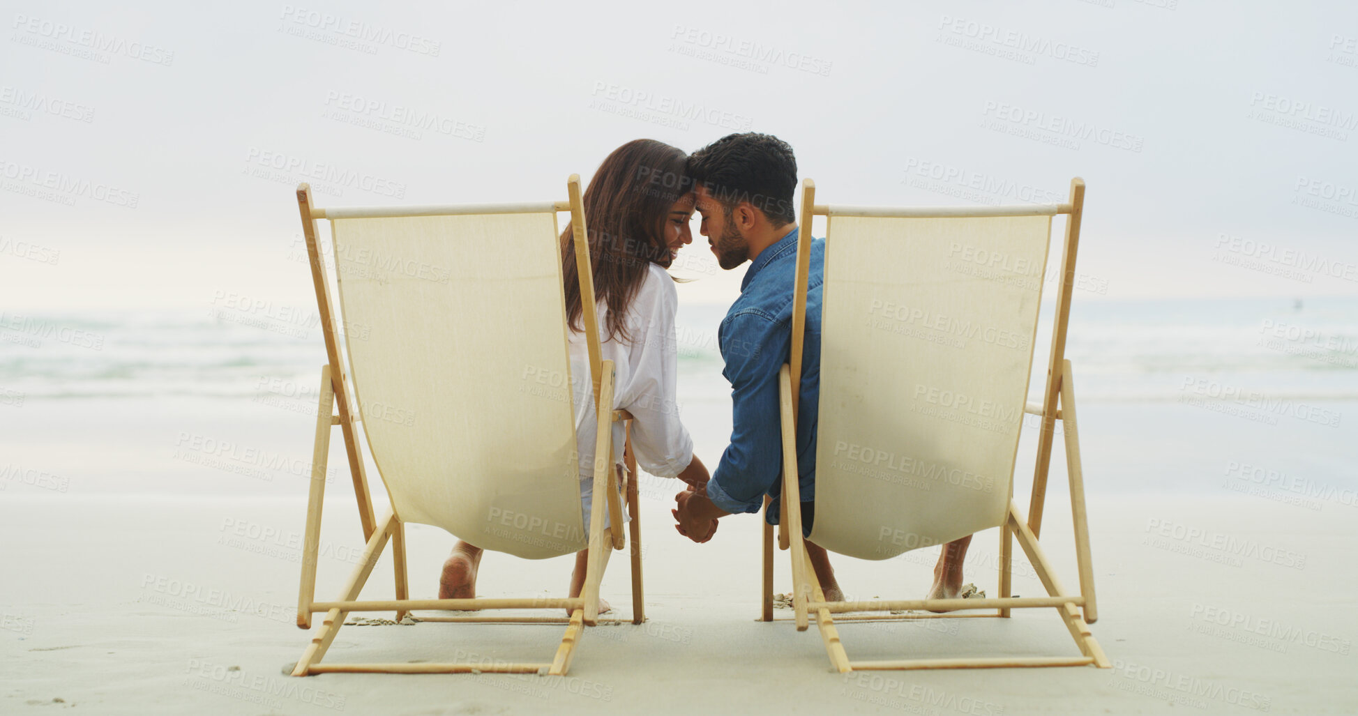 Buy stock photo Couple, beach and holding hands on vacation for honeymoon, holiday or bonding outdoor. Woman, man and relationship by sea for romantic date, chair and promise with forehead touch for connection