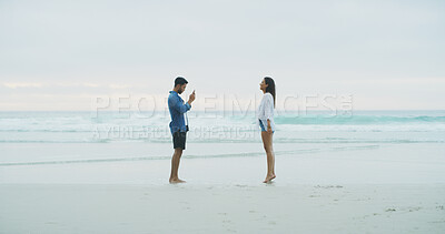 Buy stock photo Beach, couple and photograph of woman on vacation, holiday or bonding outdoor. Happy people, honeymoon and love with phone for memory, date and space with connection for social media profile picture