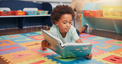Buy stock photo African boy, book and floor in classroom for development, storytelling and knowledge at academy. Child, learning and study on mat for scholarship, reading and info with course at elementary school