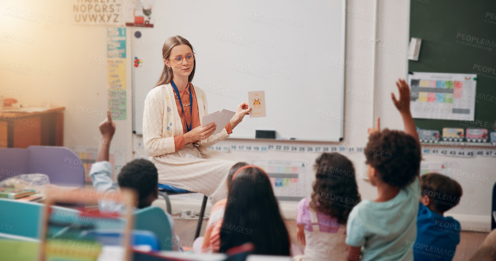 Buy stock photo Teacher, children and hand raised in classroom for question, answer and quiz card for education at academy. Woman, kids and test for animal, happy and development with learning at elementary school
