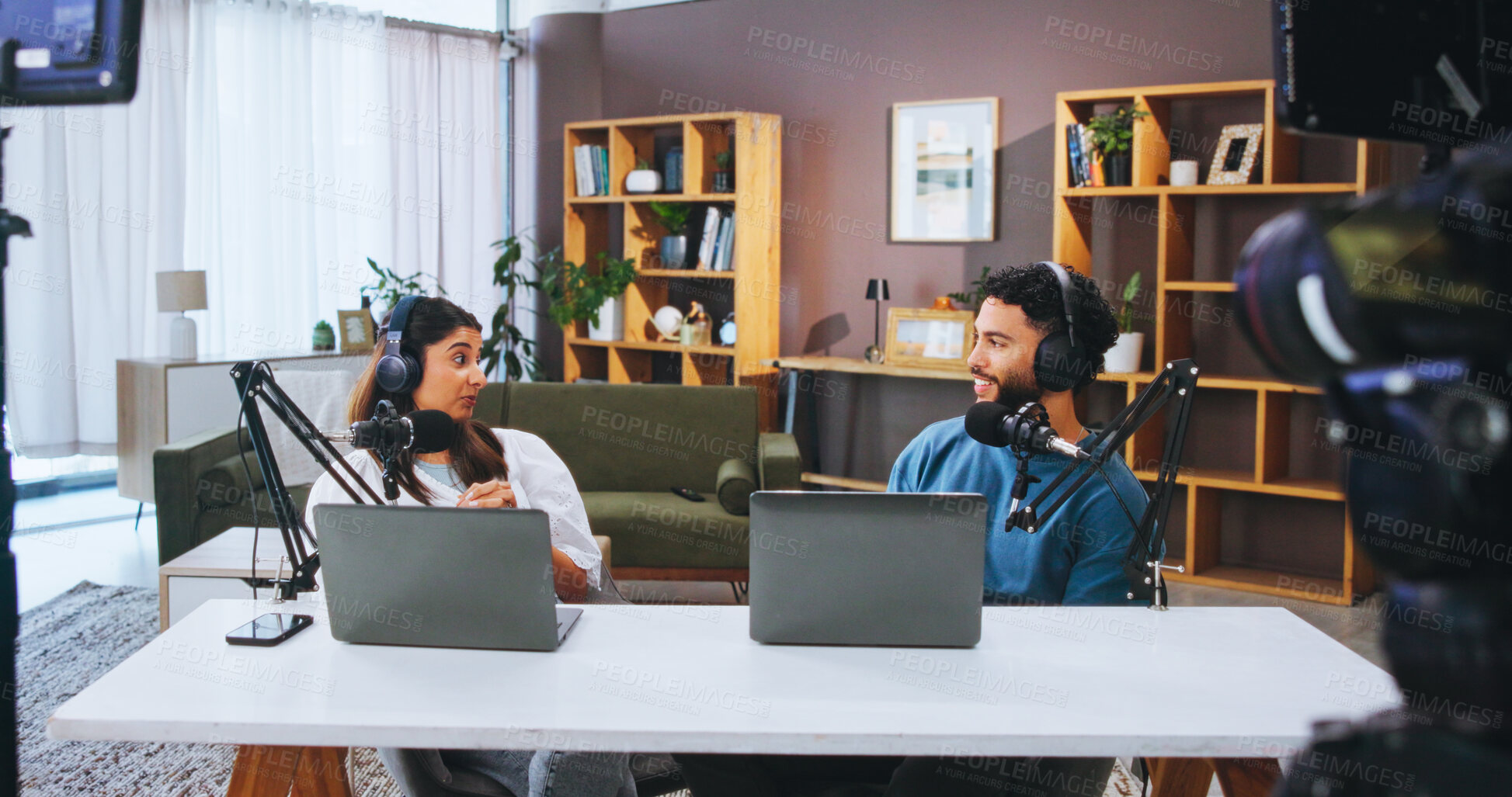 Buy stock photo Headphones, talking and people with mic on podcast in home studio for online radio show or local news broadcast. Laptop streaming, host and discussion with guest for public relations or web interview