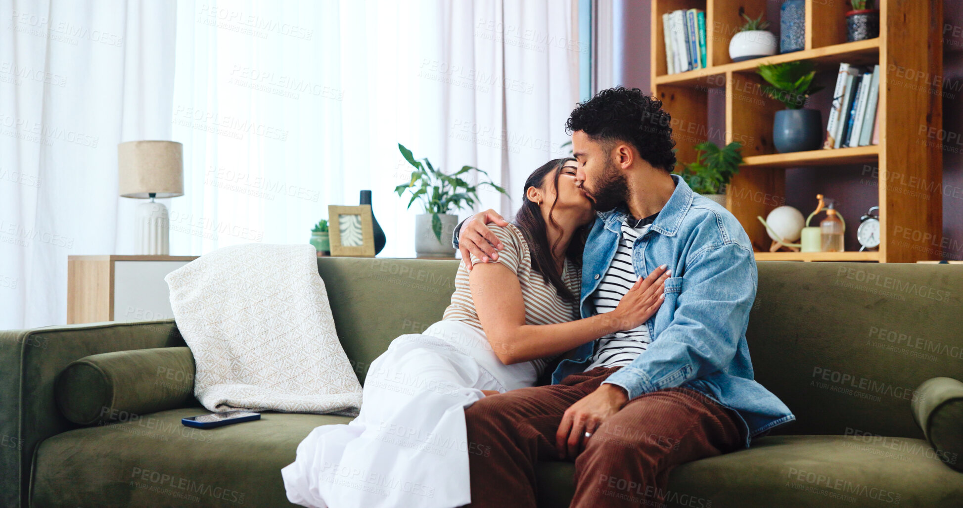 Buy stock photo Home, kissing and couple on sofa, love and bonding together with affection in lounge. Embrace, apartment and man with woman, marriage and relax with romance, relationship and happiness with care
