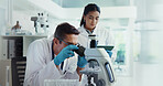 Scientist, woman and man with microscope for biotech, testing and medical research. Chemistry, laboratory and assistant with tablet report for pharmaceutical or pathology experiment for breakthrough