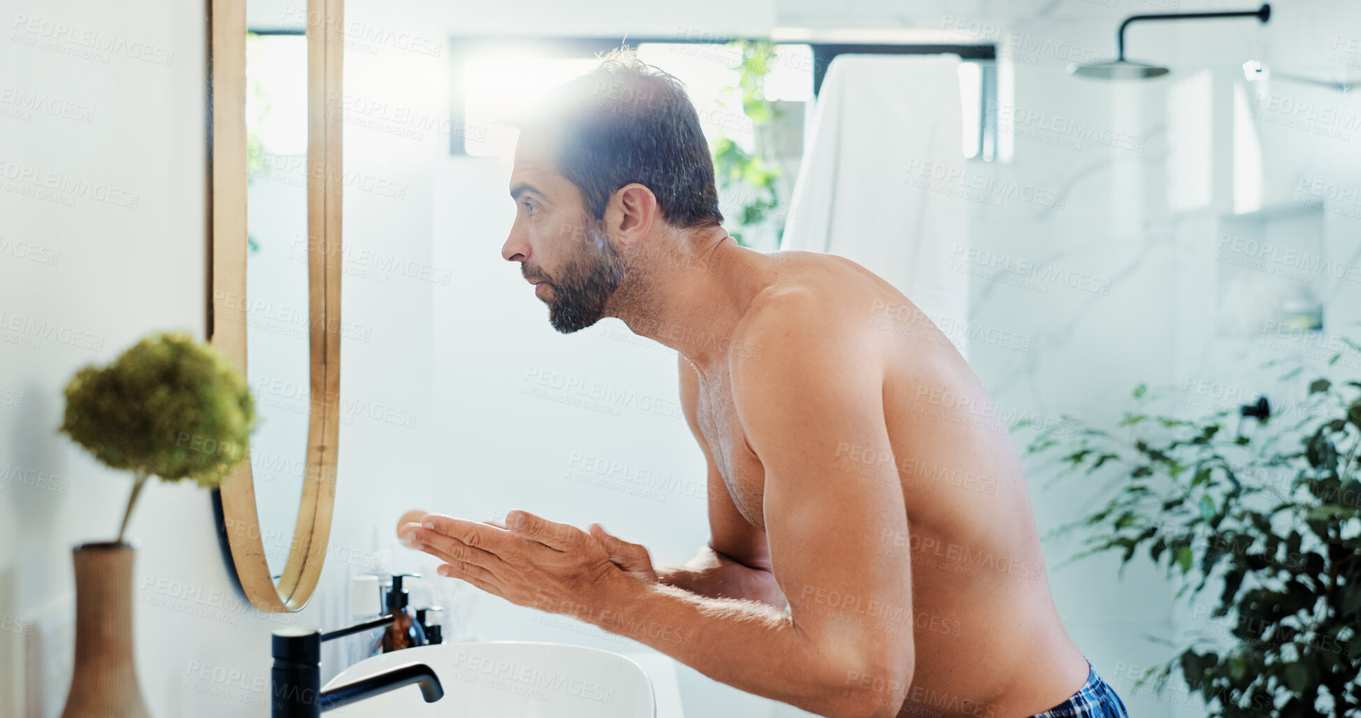 Buy stock photo Man, skincare and washing with mirror in bathroom for hygiene, anti aging or grooming in home. Male person, shirtless or face cream with SPF for facial treatment, skin protection or dermatology