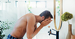 Man, face wash and water with mirror in bathroom for skincare hygiene or cleaning at home. Male person, rinse and facial treatment with hydration for morning routine, grooming or dermatology at house