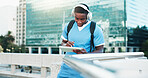 Medical student, city and black man on tablet with headphones for education, audiobook and podcast. Technology, outdoor and healthcare nurse listening to music, learning or study at college campus