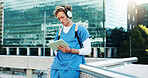 Medical student, city and man on tablet with headphones for education, audiobook and podcast. Technology, outdoor and healthcare nurse listen to music, learning or study on rooftop at college campus