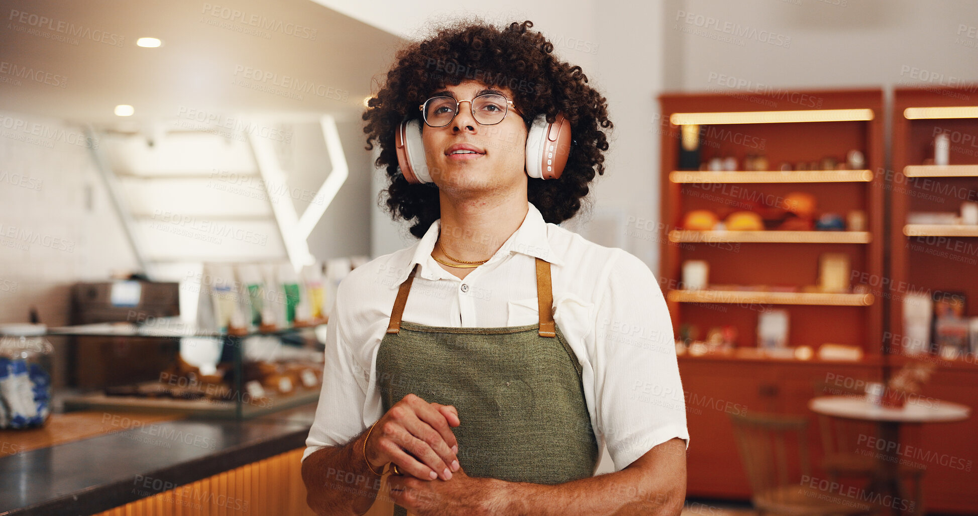 Buy stock photo Music, man and barista with headphones in cafe, streaming radio and idea for hip hop playlist in startup. Thinking, waiter and listening to sound, reflection and daydreaming for vision in coffee shop