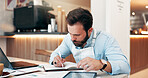 Businessman, writing and book with laptop at cafe for small business management, report or schedule. Man, employee or barista with documents or technology for inventory or checklist at coffee shop