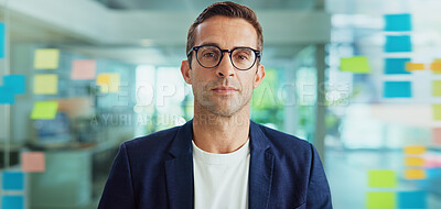 Buy stock photo Portrait, creative and business man with glasses in office or serious journalist in startup. Face, confident worker or entrepreneur, news editor or employee with vision by glass wall with sticky note