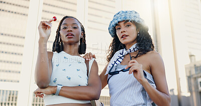 Buy stock photo Streetwear, cool and women in city with fashion or lollipop for urban, edgy and trendy style together. Low angle, gen z friends and creative people in town for youth culture, unique outfit and swag