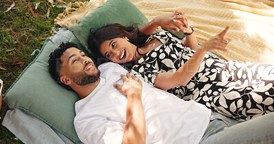 Buy stock photo Outdoor, pointing and couple on date, picnic and smile for conversation in nature, embrace and relationship. Happy, man and bonding with woman on anniversary, people and cloud watching for romance