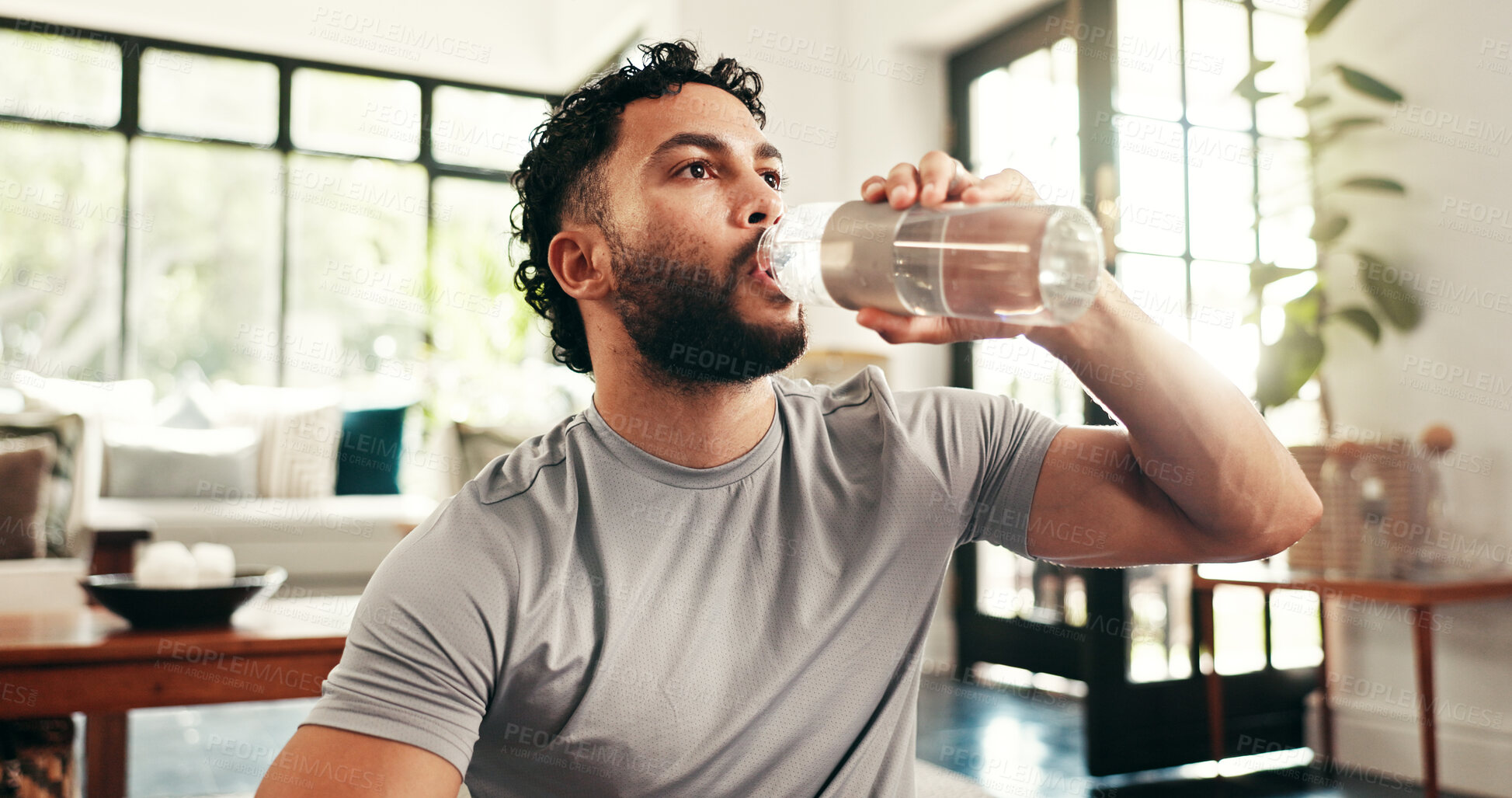 Buy stock photo Break, drinking water and fitness with man in home for exercise, hydration or wellness workout. Bottle, relax and training with thirsty person in living room of apartment for challenge or health