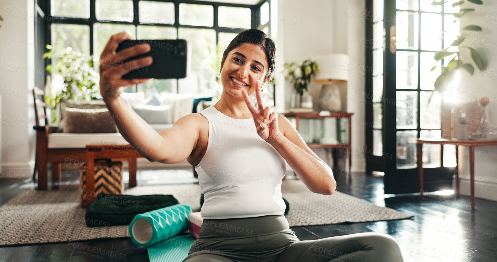 Buy stock photo Peace sign, selfie and yoga with woman in living room of home for health, pilates or wellness routine. Exercise, holistic and social media with Indian person on floor of apartment for mindful balance