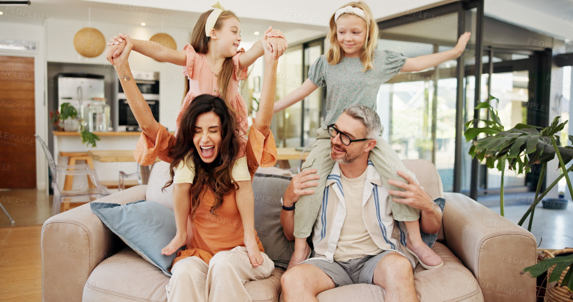 Buy stock photo Energy, playing and kids on shoulders of parents in living room of home for excitement or fun together. Daughter siblings, father and mother on sofa in apartment for bonding or games as happy family