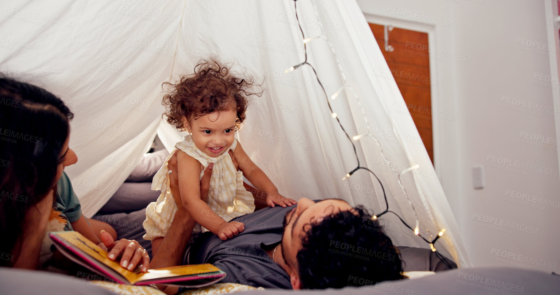 Buy stock photo Tent, parents and play with baby in home for bonding together, story time and connection with trust. Book, people and fun activity with child in blanket fort for happy relationship, love or care