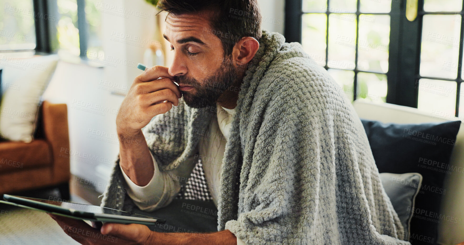 Buy stock photo Tablet, man and sick with thermometer on sofa, check fever and influenza with research for symptoms. Home, male person and illness with temperature for flu, consultation and telehealth with digital