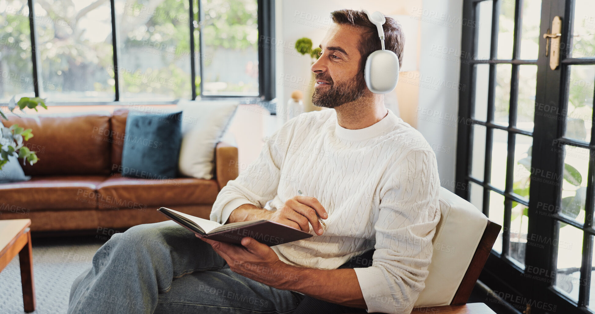 Buy stock photo Home, man and thinking with headphones for notebook, writing thoughts and personal reflection with music. Sofa, male person and ideas with audio track for journal, diary and to do list in living room