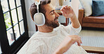 Headphones, relax and happy man in home with audio, podcast or music streaming service. Peace, sound and person resting in living room for calm, comfort and listening to song on technology to chill