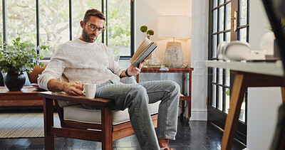 Buy stock photo Coffee, reading and relax with man on chair in living room of home for break, satisfaction or wellness. Book, stress free and time off with person in apartment for morning or weekend literature