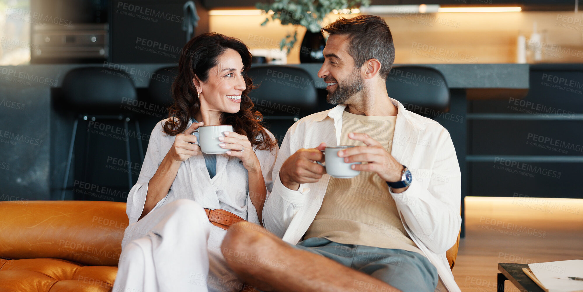 Buy stock photo Home, smile and couple with coffee, conversation and bonding together in living room. Love, latte and man with woman on sofa, herbal tea and relationship with discussion, romance and relax with care