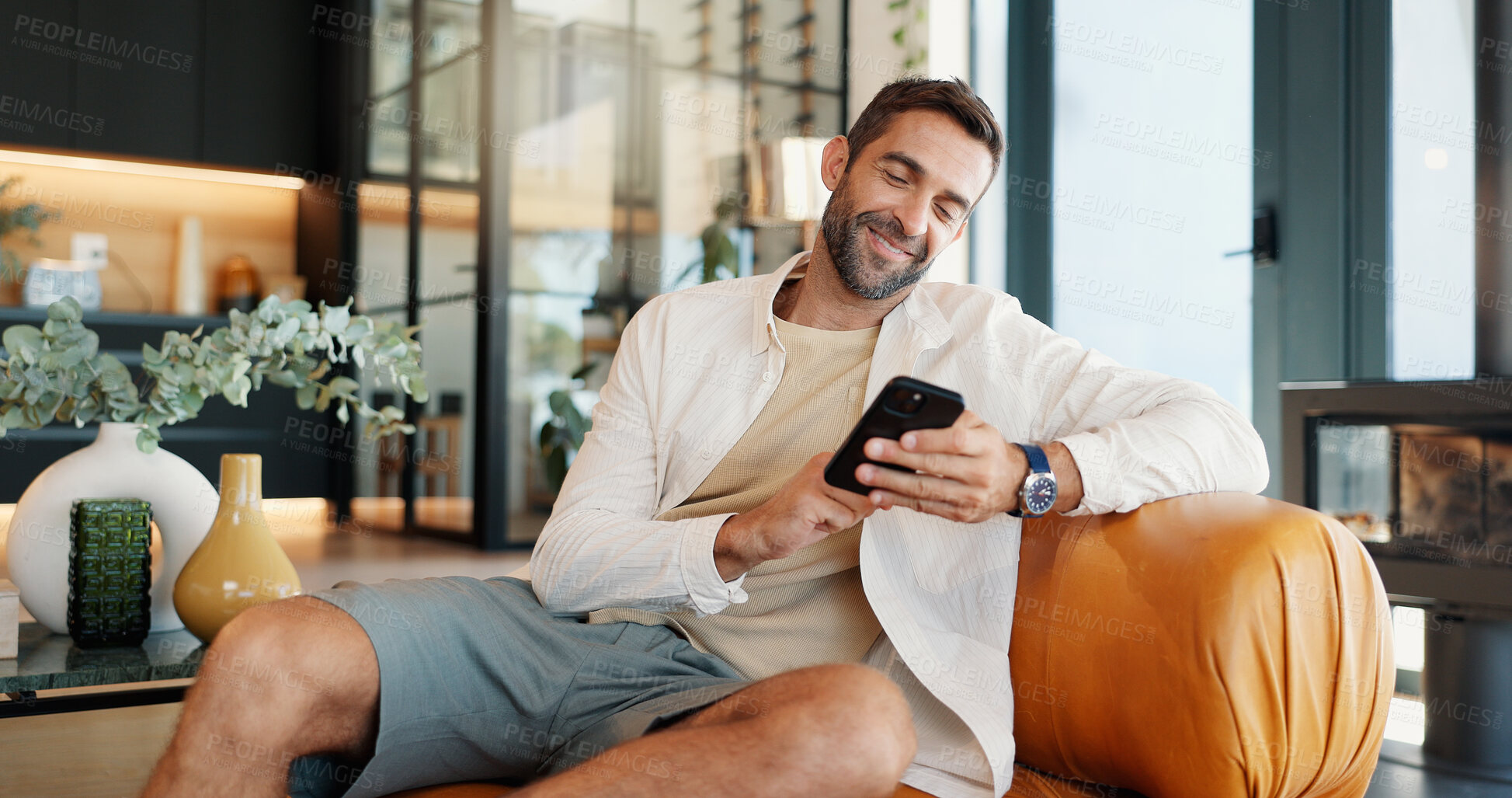 Buy stock photo Home, relax and man on sofa, smartphone and smile with message to contact, social media and connection. Person, apartment or guy on couch, cellphone and internet with funny meme or email notification