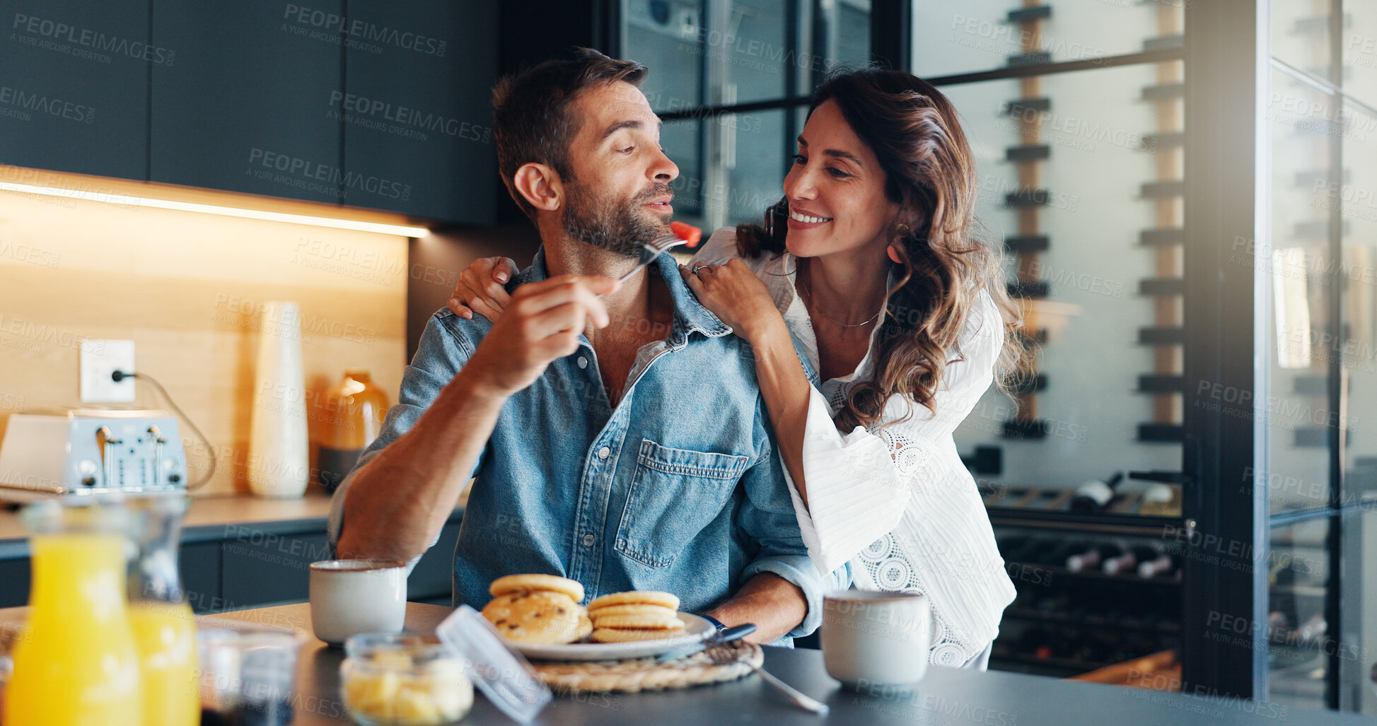 Buy stock photo Feeding, happy and couple with breakfast in kitchen for romance on weekend morning together. Love, eating and woman with man for healthy meal for nutrition with fun in marriage in home with helping.