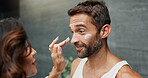 Skincare, couple and cream on face in bathroom for skin hydration, morning routine or moisturizer. Love, people or happy with product application for sunscreen, dermatology support or bonding in home