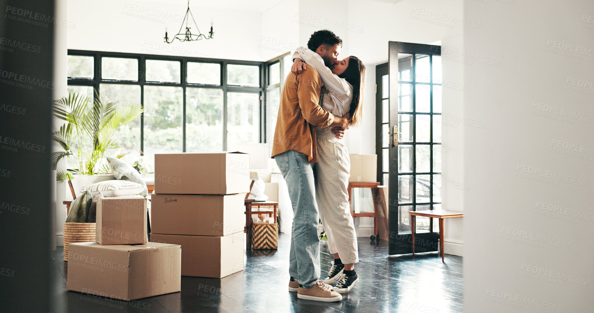 Buy stock photo Celebration, kiss and couple in new house, moving and ownership of property with mortgage or real estate. Relocation, love and people with boxes in living room, investment or hug for purchase of home