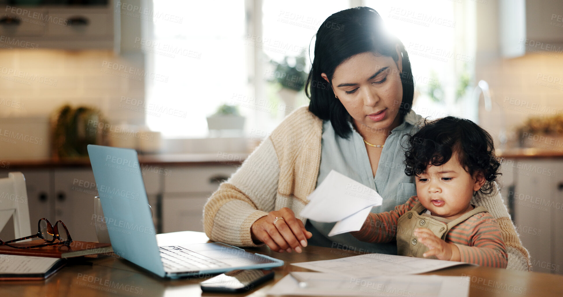 Buy stock photo Distraction, child and mom with laptop, remote work and bookkeeper with paperwork in kitchen, family and online. Multitasking, mother and care for baby in house, accountant and person with documents