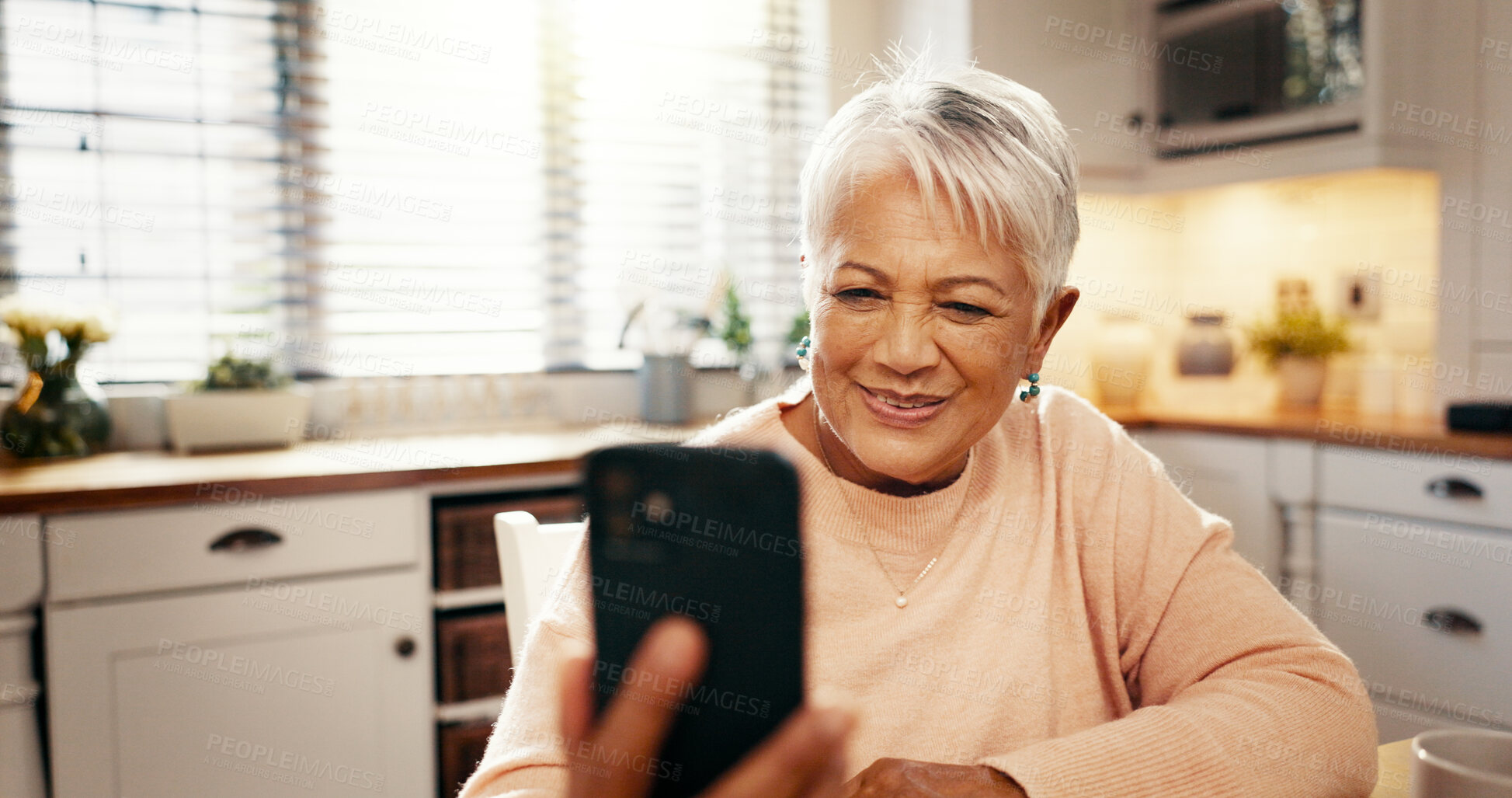 Buy stock photo Phone, video call and senior woman in kitchen with communication, networking or contact. Happy, technology and elderly female person with cellphone for virtual conversation on mobile app in home.