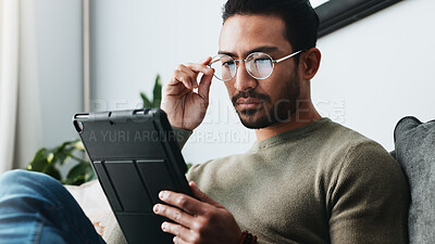 Buy stock photo Tablet, glasses and man on sofa in home reading online blog, post or news article for politics. Digital technology, research and male person with social networking in living room at apartment.