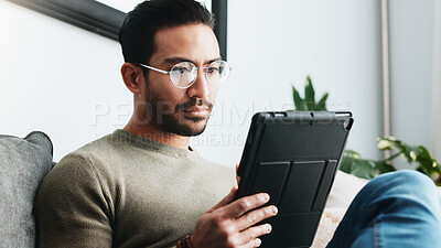 Buy stock photo Tablet, research and man on sofa in house reading online blog, post or news article for politics. Digital technology, glasses and male person with social networking in living room at apartment.