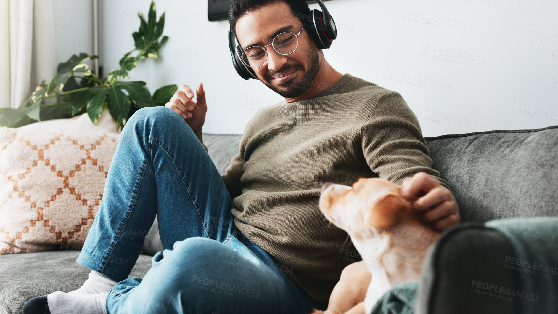 Buy stock photo Man, relax and headphones with dog on couch for listening to music, podcast audio and animal affection. Person, rest and puppy for streaming radio, playlist sound and bonding with loyal pet at house