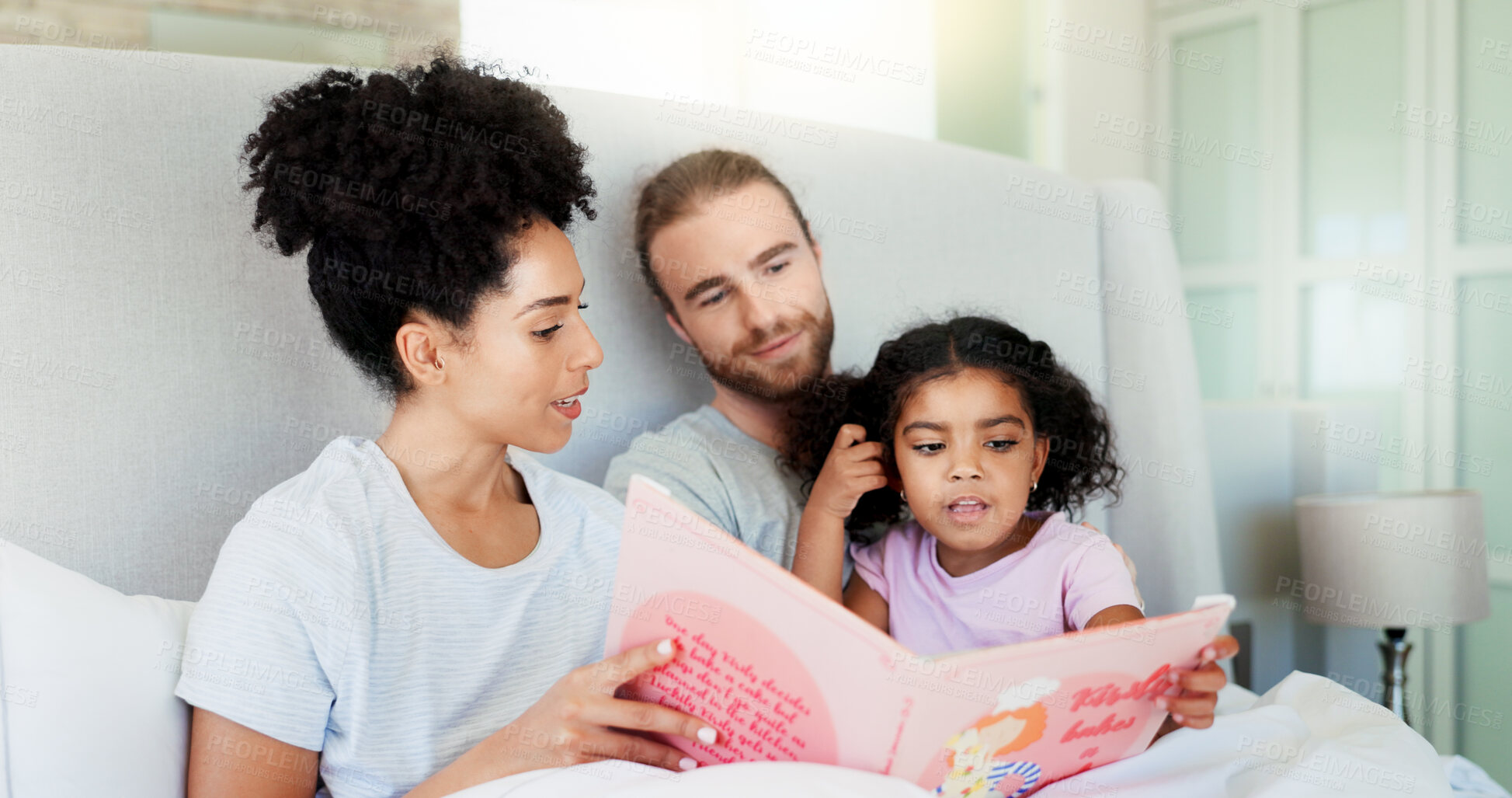 Buy stock photo Parents, girl and story book in bed for reading, happy and learning with care, guide or language in home. Father, mother and daughter with relax, love or smile for bonding at interracial family house